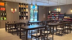 Un intérieur moderne avec de nombreuses tables et chaises en bois, des étagères remplies de produits et des lampes suspendues.