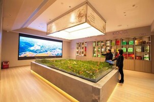 Un vestíbulo de hotel con una gran pantalla digital, una mesa de recepción y una exhibición de servicios.