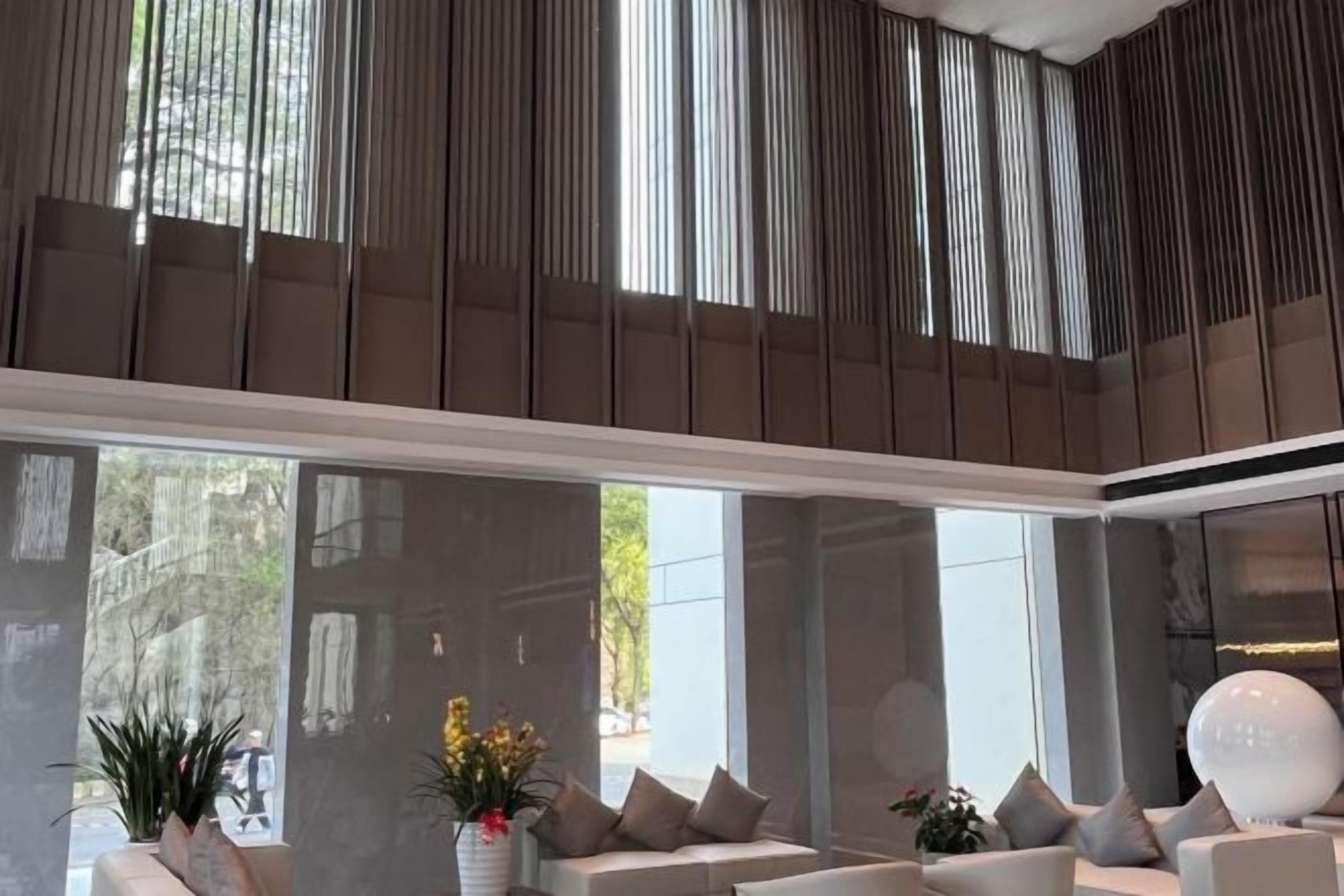 A modern interior with a high ceiling, large windows, and a seating area with sofas and a white spherical object.