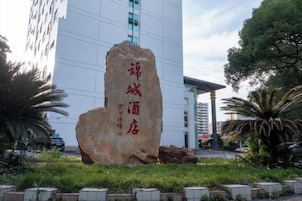 Una gran piedra con caracteres chinos frente a un edificio moderno.