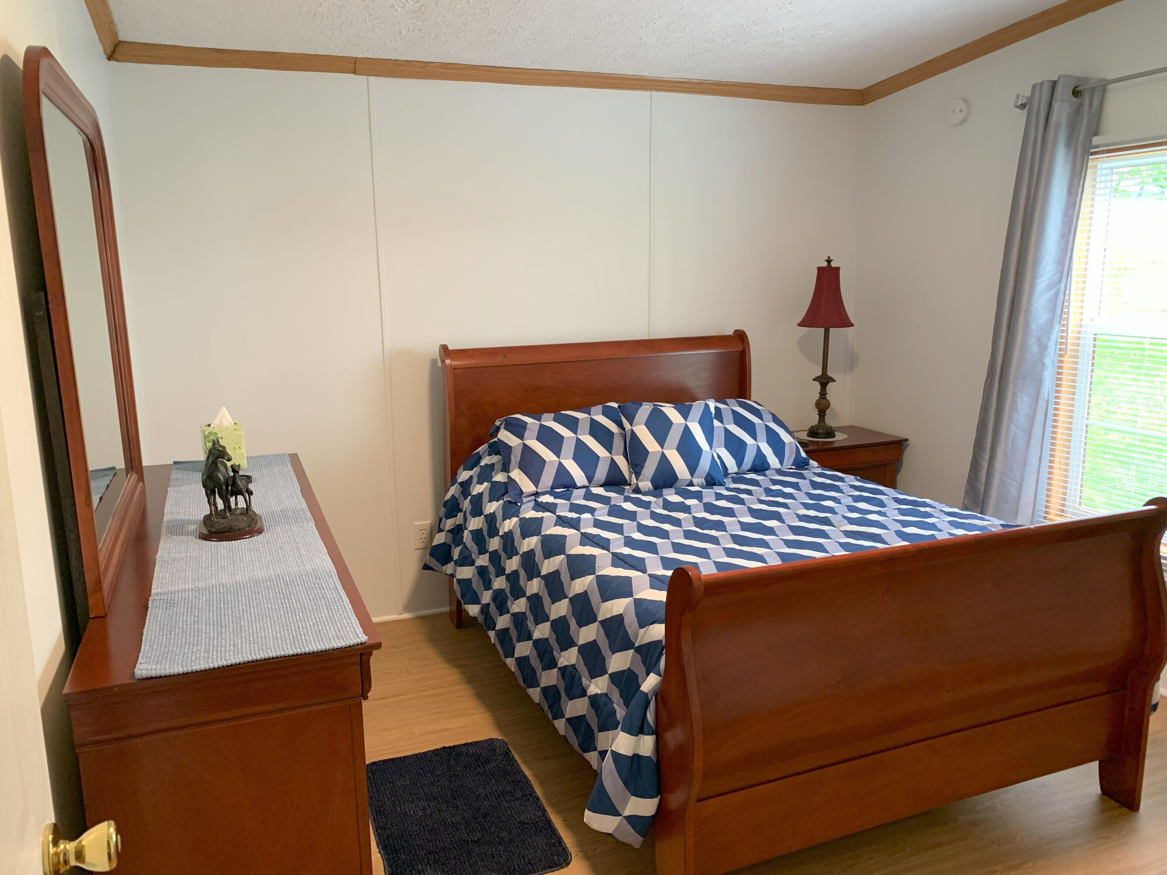 Une chambre à coucher avec un lit en bois, une table de chevet avec une lampe, un miroir et une petite statue.