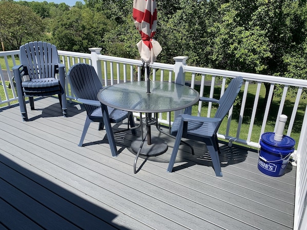 Une terrasse dotée d’une table ronde en verre et de quatre chaises, entourée d’une rambarde blanche.