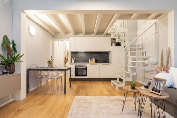 A modern kitchen with a built-in oven and a staircase leading to an upper level.