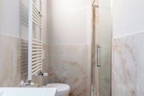 A modern bathroom with a toilet, a shower enclosure, and a built-in towel rack.