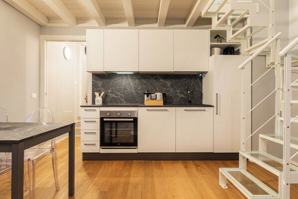 A modern kitchen with white cabinets, a black countertop, and a built-in oven.