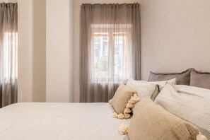 A bedroom with a bed, curtains, and a window.