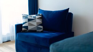 Ein blauer Sessel mit einem geometrisch gemusterten Kissen und einem einfarbigen blauen Kissen.
