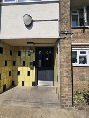 Fachada de edificio con azulejos, una puerta y un ventanal pequeño.