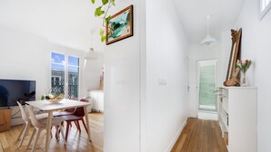 A modern kitchen with white cabinets, a dining area with a wooden table and chairs, and a large window providing natural light. - Wow view top Paris City centre (Paris)