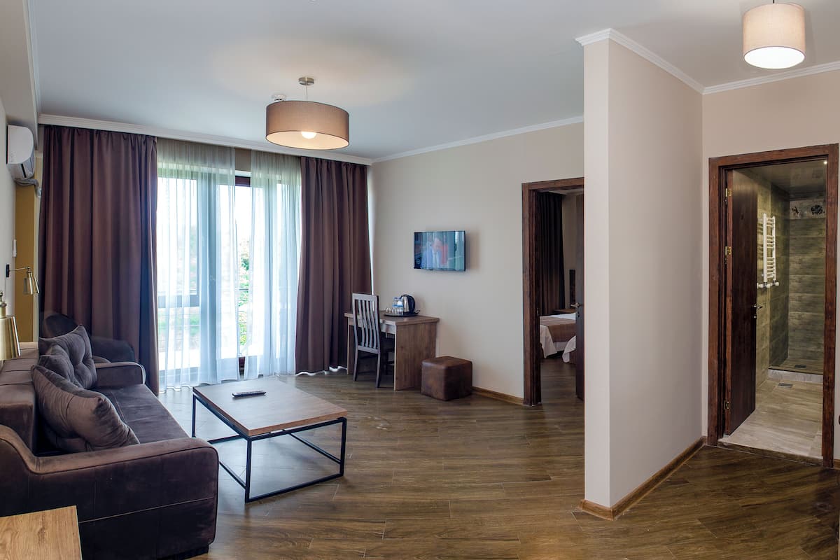 Una sala de estar moderna con un sofá, una mesa de centro y un televisor. Se ve un comedor con una mesa y sillas, y un baño visible a través de una puerta abierta.
