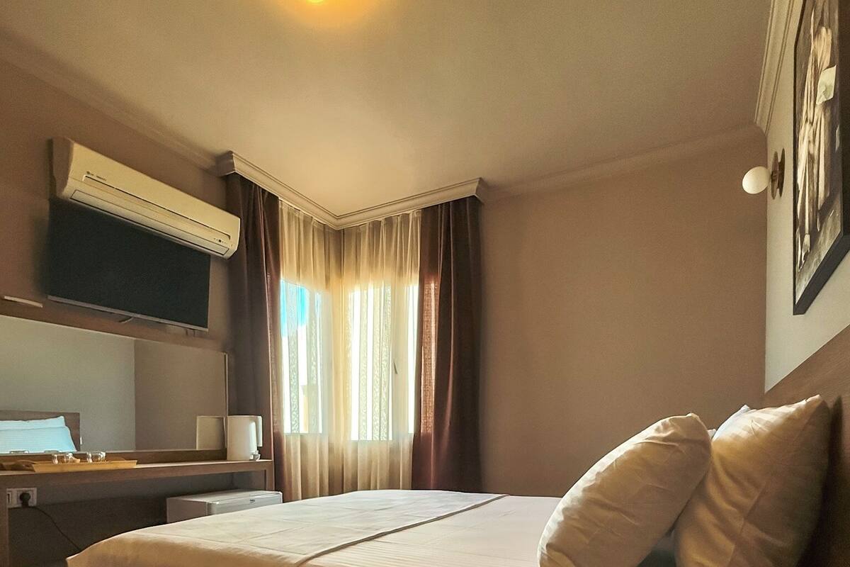 Ein Hotelzimmer mit einem Bett, einem Schreibtisch, einem Flachbildfernseher und einem Fenster mit Vorhängen.
