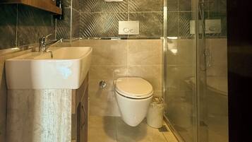 Un baño con lavamanos, inodoro y cabina de ducha de vidrio.