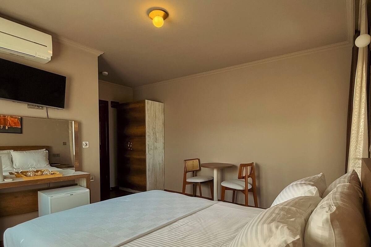 Ein Hotelzimmer mit einem großen Bett, einem Schreibtisch mit Stuhl, einem Fernseher und einem kleinen Kühlschrank.
