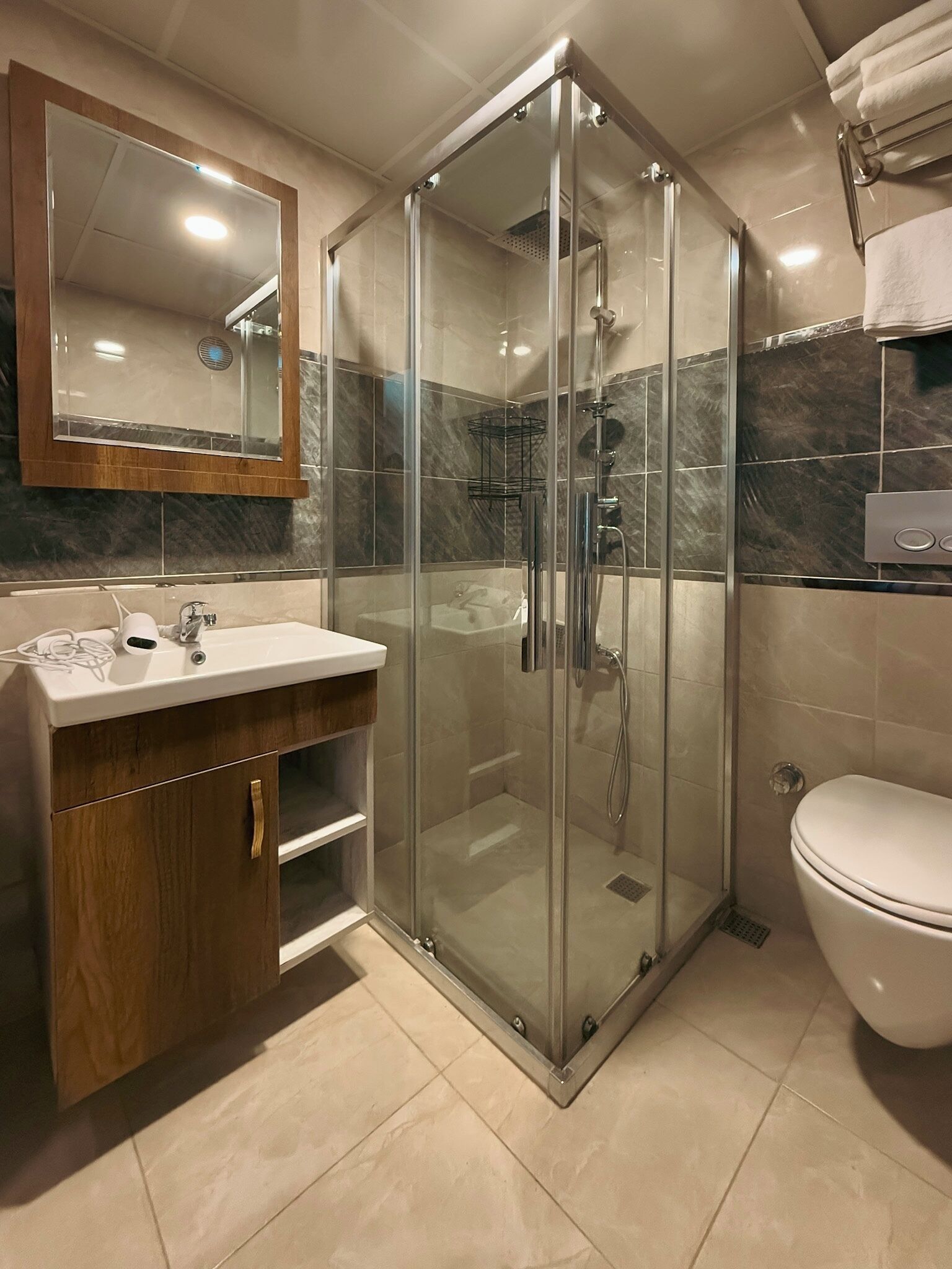 A modern bathroom with a glass-enclosed shower, a vanity with a mirror, and a toilet.