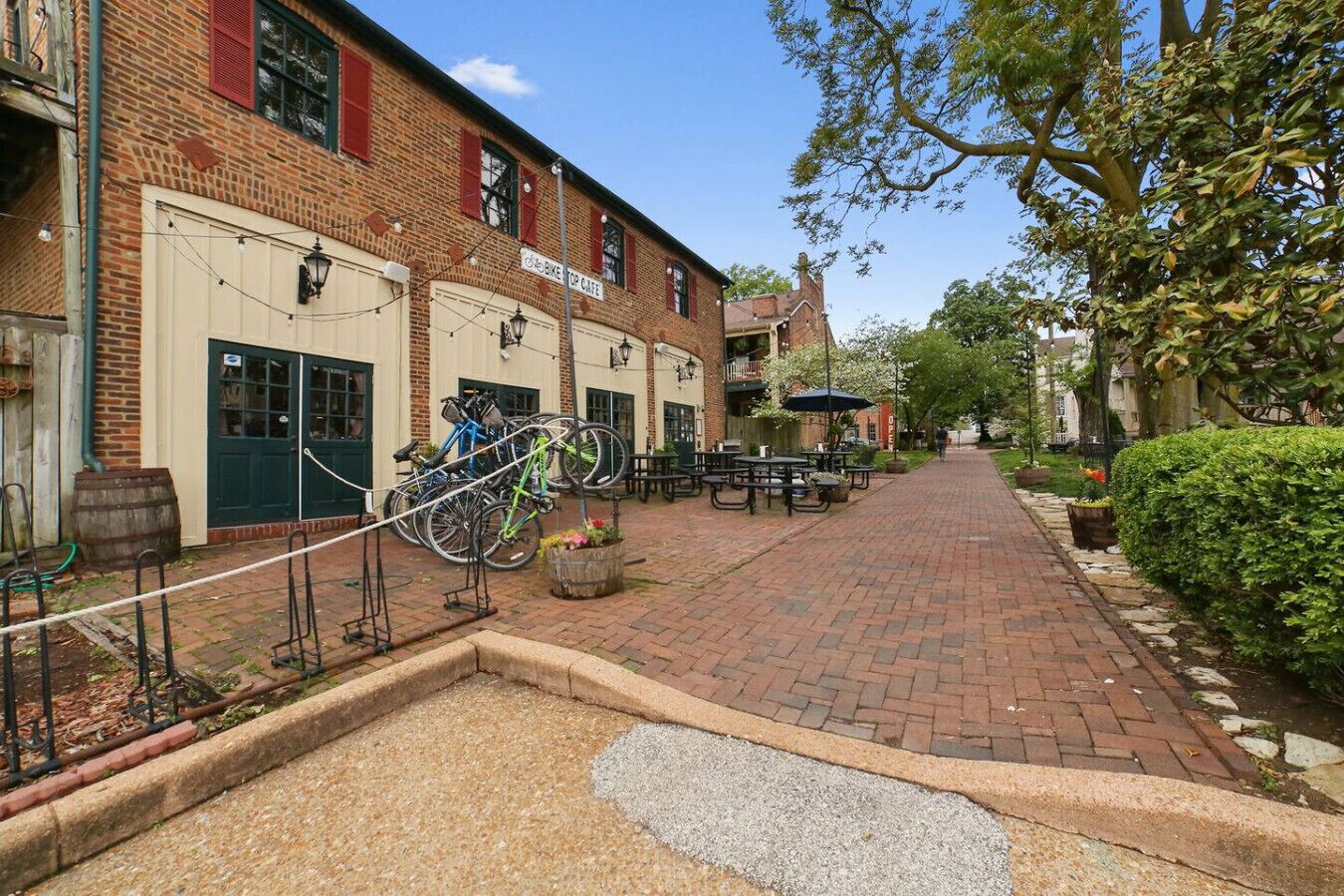 Un edificio de ladrillo con un letrero que dice 'Old Bike Stop Cafe', mesas al aire libre y bicicletas estacionadas afuera.