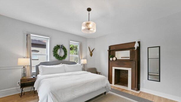 Un dormitorio con cama, chimenea, espejo y un adorno colgante.