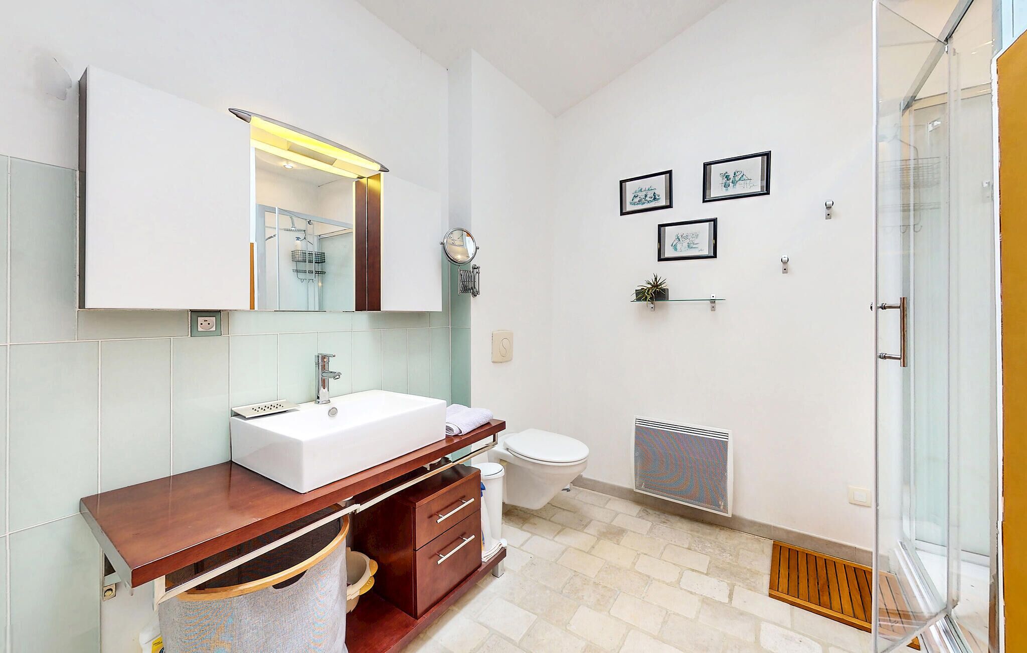 A modern bathroom with a white sink, wooden vanity, and a glass shower enclosure.