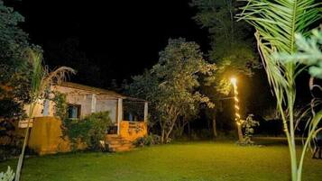 Una casa con veranda, circondata dal verde e da un giardino illuminato di notte.
