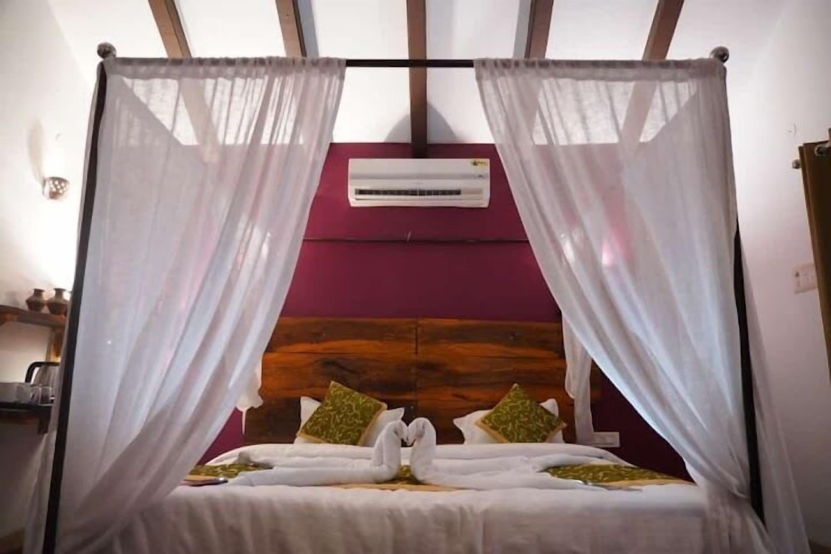 A bed with a canopy, a wall-mounted air conditioner, and a wooden headboard.