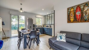 Een moderne keuken met een eethoek, een bank en een schilderij van surfboards.