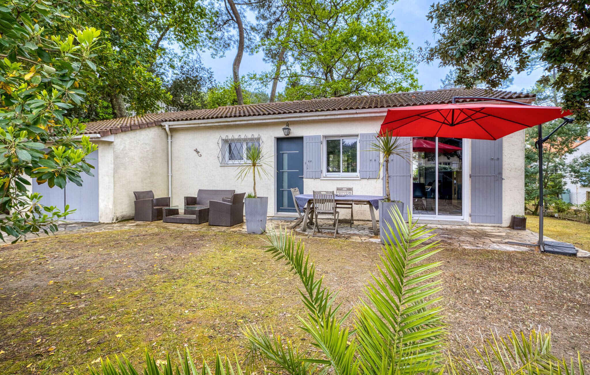 A house with a patio, outdoor furniture, and a red umbrella.