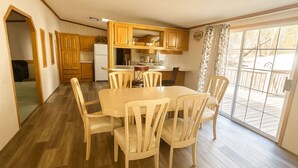 Une cuisine compacte avec des meubles en bois, une table à manger avec des chaises et une porte-fenêtre coulissante donnant sur un espace extérieur.