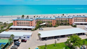 A hotel with multiple buildings, a parking area, and a beach view.