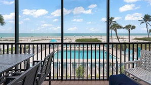 A balcony with a view of a beach and a pool.