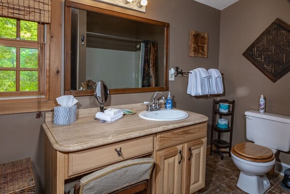 A bathroom with a wooden vanity, a sink, a mirror, and a toilet.