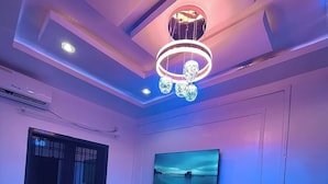 Un soggiorno moderno con televisione a schermo piatto montata a parete, un lampadario di design e un'ampia finestra con vista.