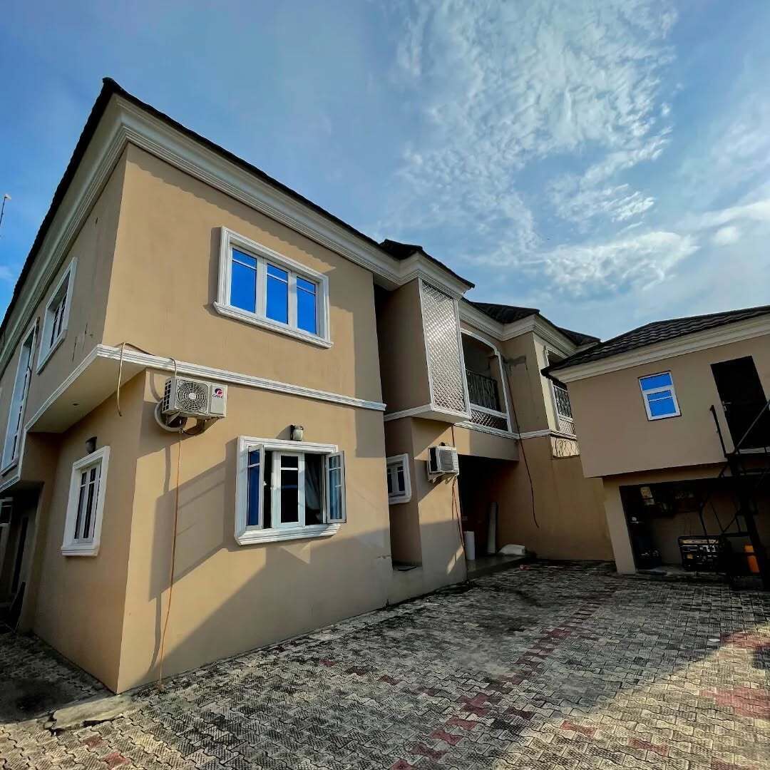 A two-story building with multiple windows, air conditioning units, and a paved courtyard.