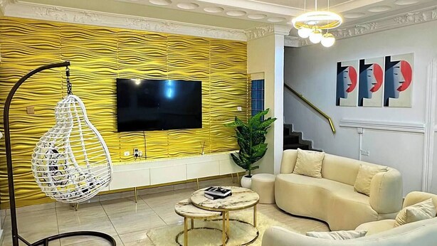 Un soggiorno moderno con un divano, una poltrona sospesa, un tavolino da caffè e una TV a parete.