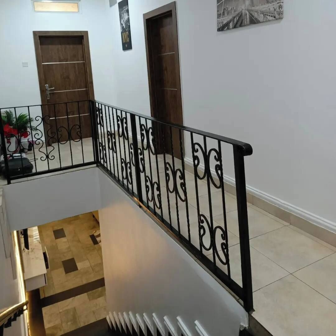 Una escala amb barana de metall negre, portes de fusta i terra de rajola.