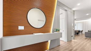 Un espace d'accueil avec un mur composé de lambris en bois, un grand miroir rond et un comptoir de réception.