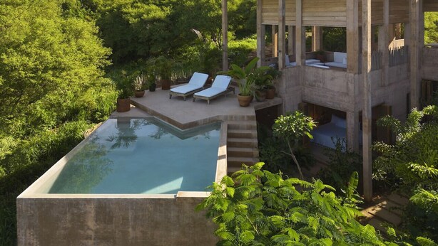 Un área de piscina moderna al aire libre con sillones de descanso y una estructura de hormigón.