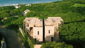 A modern building with a symmetrical design, surrounded by lush greenery and a coastal view.