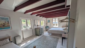 A bedroom with two beds, a dresser, a radiator, and a large window. - Charming house - Swimming pool - 11 beds - 15 travellers - Pets OK - Cluny (Azé)