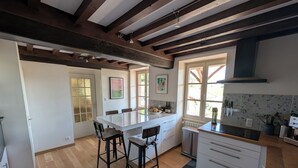A modern kitchen with a large island, wooden flooring, and a view of the outdoors. - Charming house - Swimming pool - 11 beds - 15 travellers - Pets OK - Cluny (Azé)
