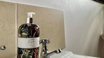 A bathroom with a sink, a floral bottle of hand soap, and a mirror with an ornate frame.