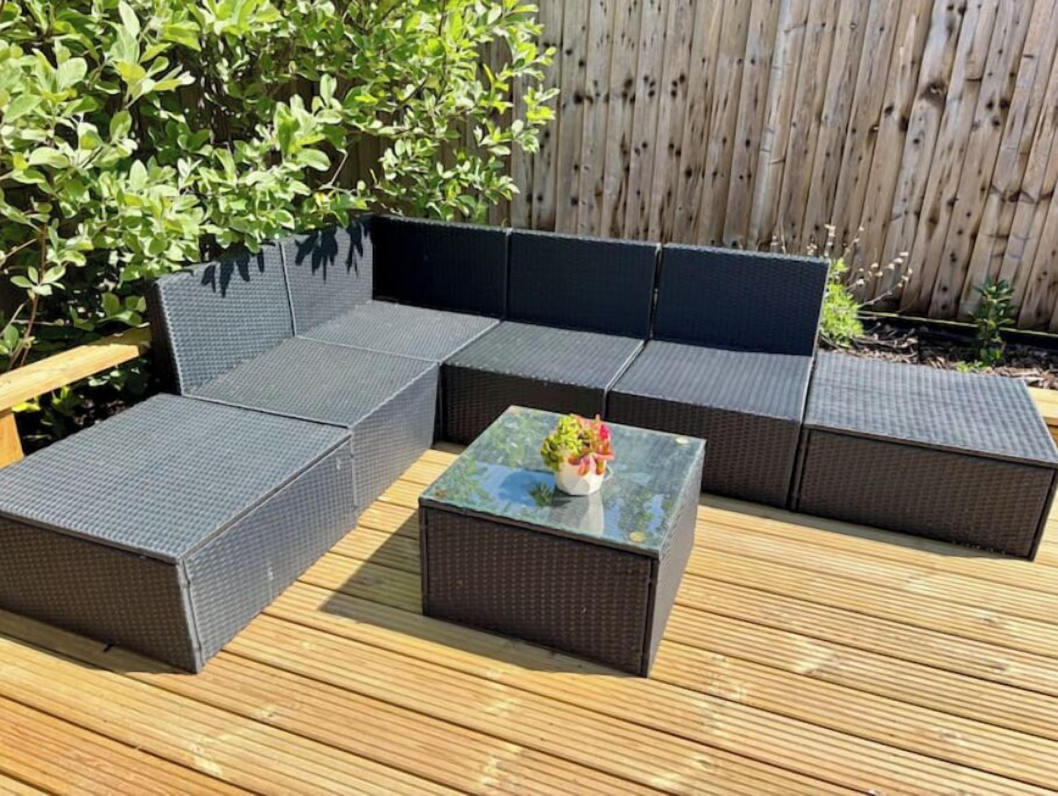 A sectional sofa and a small table on a wooden deck.