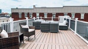 Une terrasse sur le toit, dotée de meubles en osier et d’une rambarde blanche.