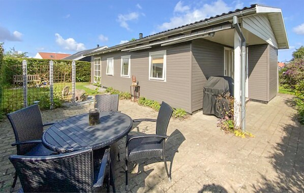 A house with a patio area featuring a round table and chairs, a grill, and a covered outdoor space.