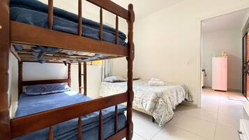 Una habitación con una litera, una cama individual y un refrigerador.