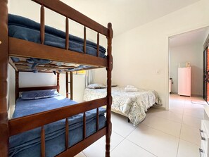 Una stanza con un letto a castello, un letto singolo e un frigorifero.