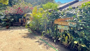 A garden area with a wooden sign indicating 'ARACUA LAGUNA BEACH' and 'VISITE MOTHES DA BARRA'. - Pousada Aracuã - Laguna (Laguna)