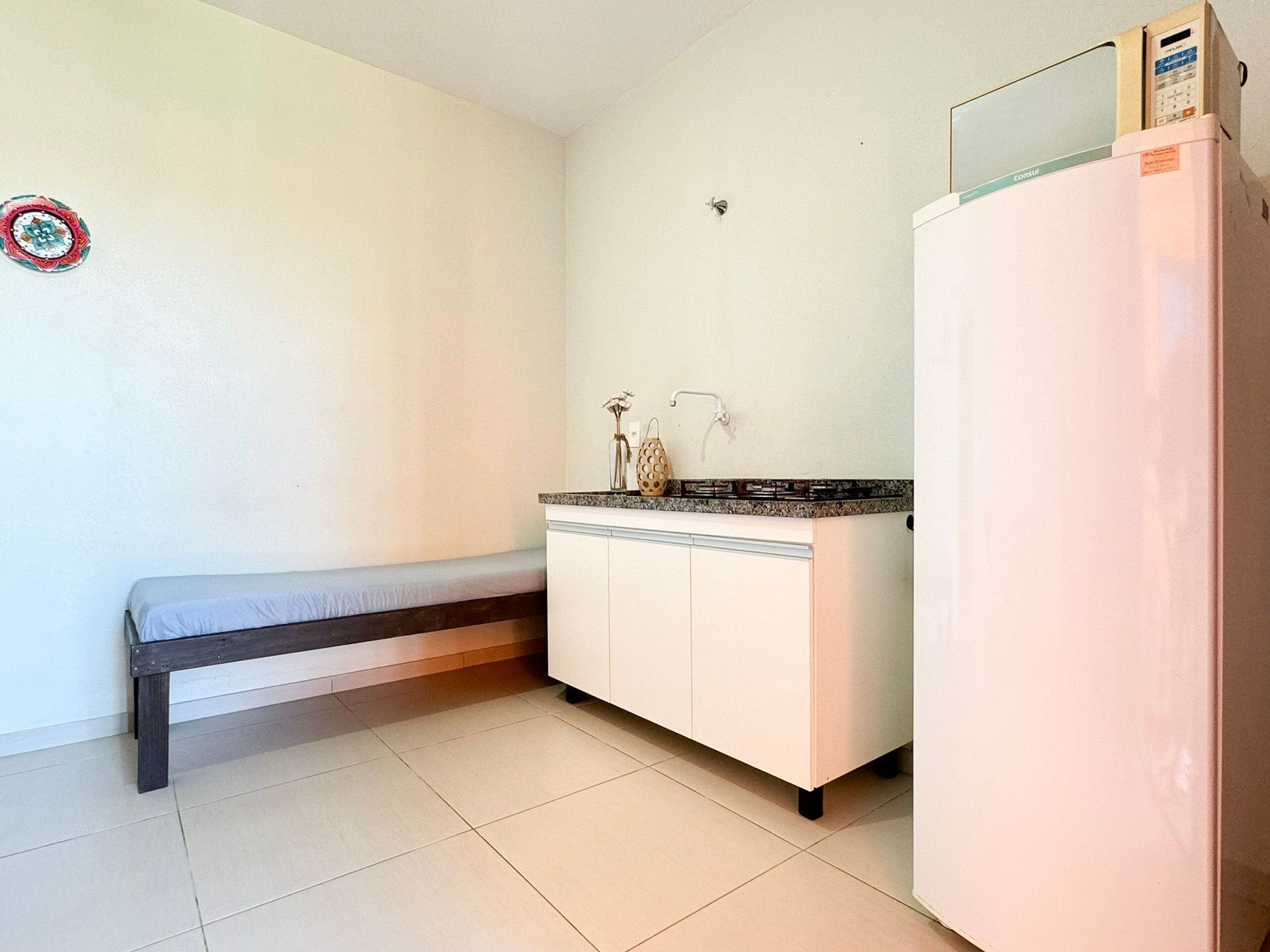 Una pequeña kitchenette con un refrigerador blanco, una encimera y un banco.