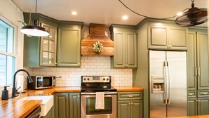 A kitchen with green cabinets, a stainless steel oven, a microwave, and a refrigerator. - Creekside Retreat w/ Hot Tub + Game Room, 6 minutes to Downtown, 15 to Folly! (Charleston)
