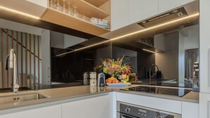Una cocina moderna con horno empotrado, pileta de acero inoxidable y una encimera con un jarrón de flores.
