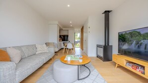 Una sala de estar moderna con un sofá gris, una mesa de centro, un televisor y una chimenea.