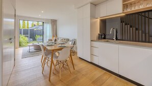 Una cocina moderna con armarios blancos, una mesa de comedor de madera y vistas al exterior.